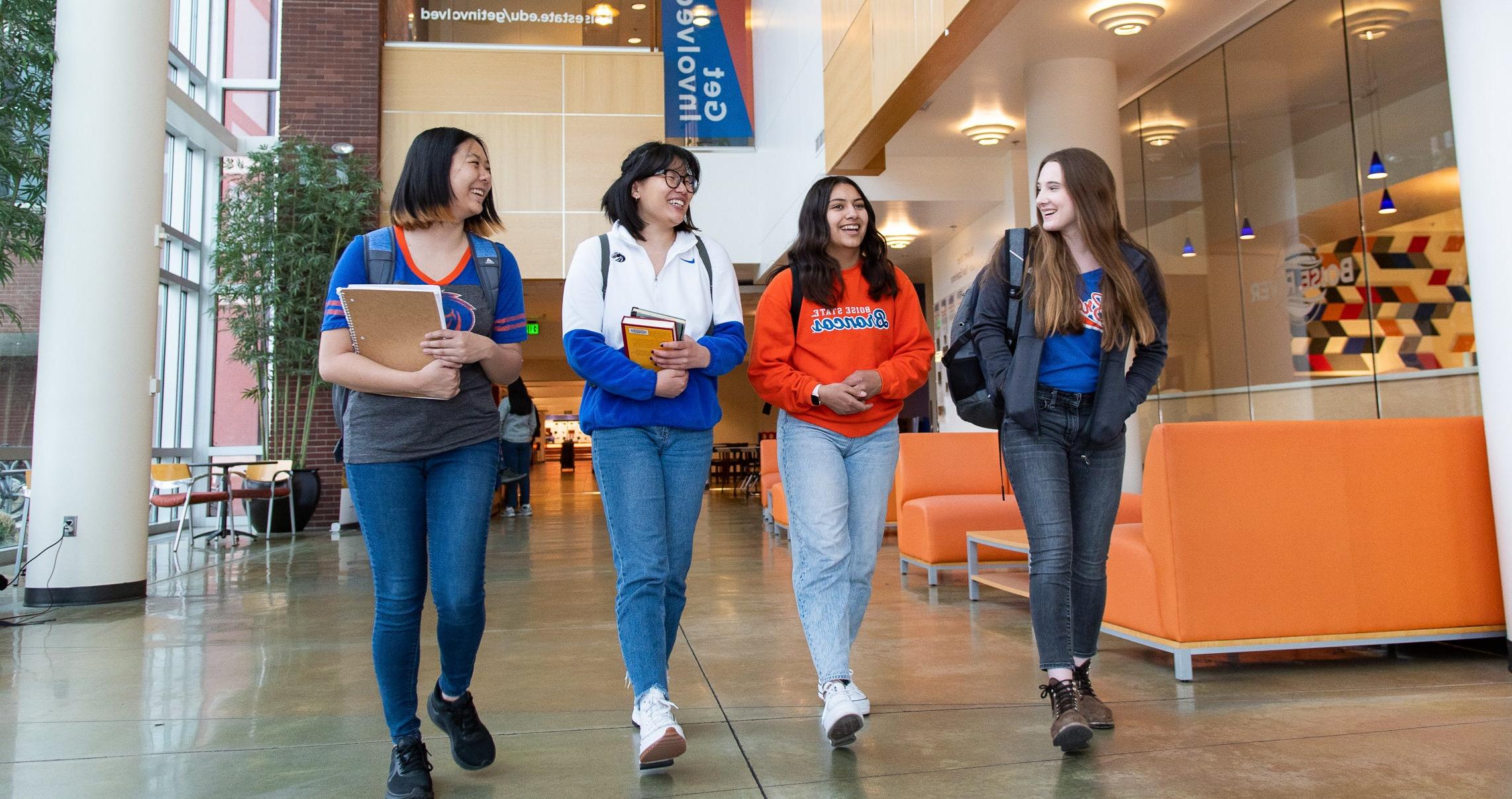 group of 4 students walking and talking on campus